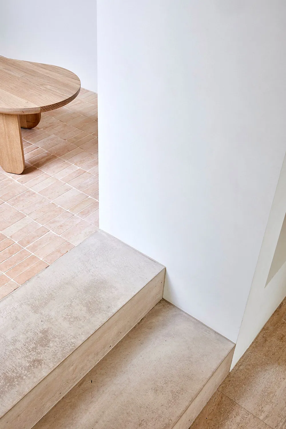 A minimalist concrete staircase with a smooth, textured surface, placed against a white wall in a contemporary interior desig