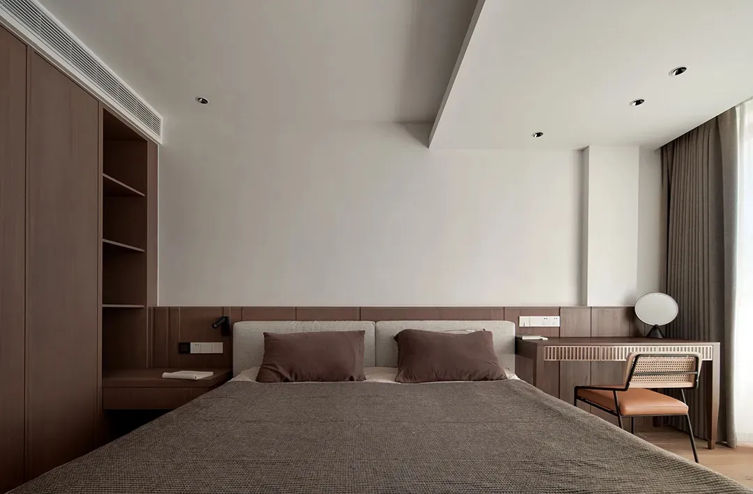 A modern bedroom with a wooden headboard and wall, featuring a gray bed and brown accents.