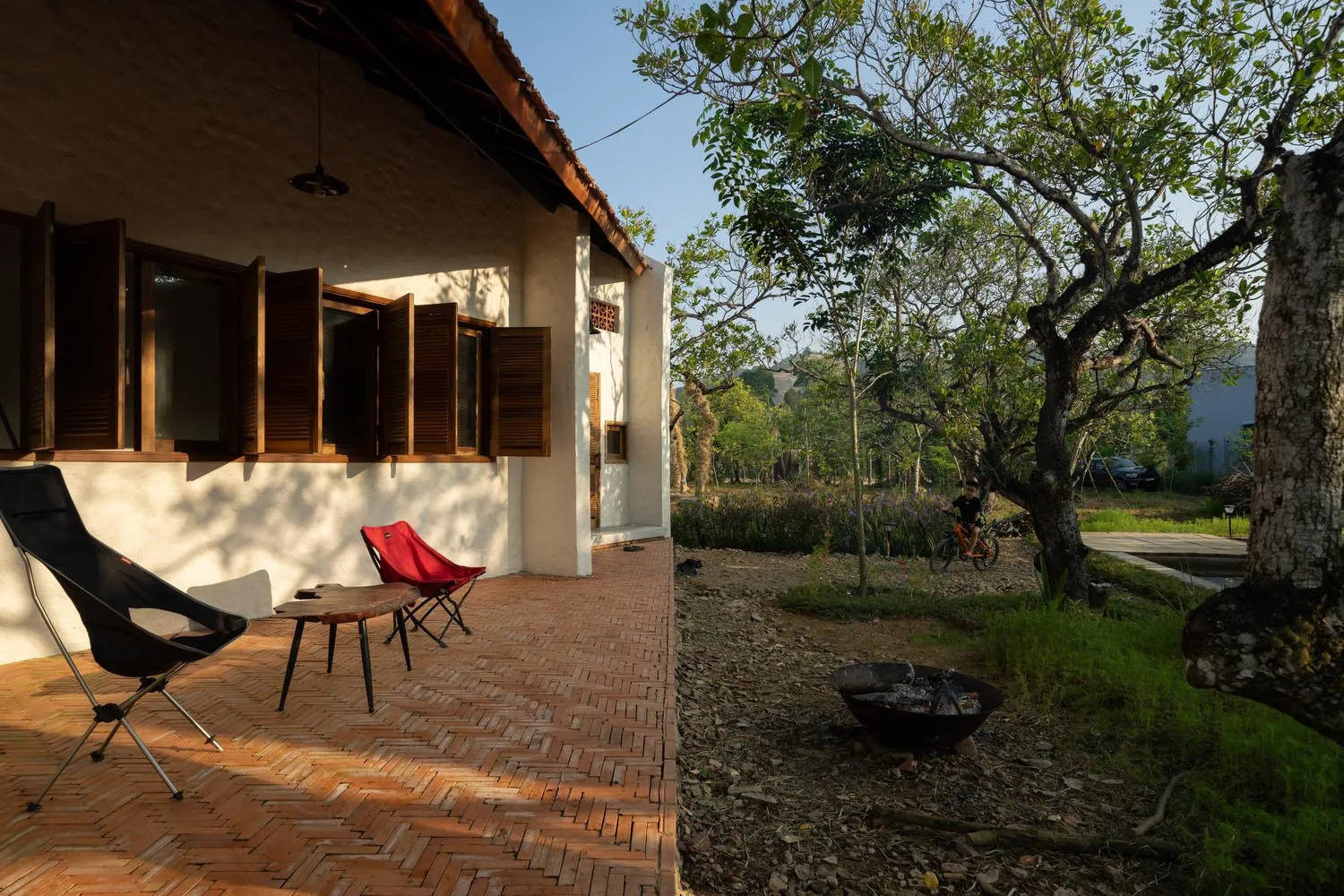 Modern residential exterior with wood hexagonal pattern, featuring wooden shutters and a brick patio area.