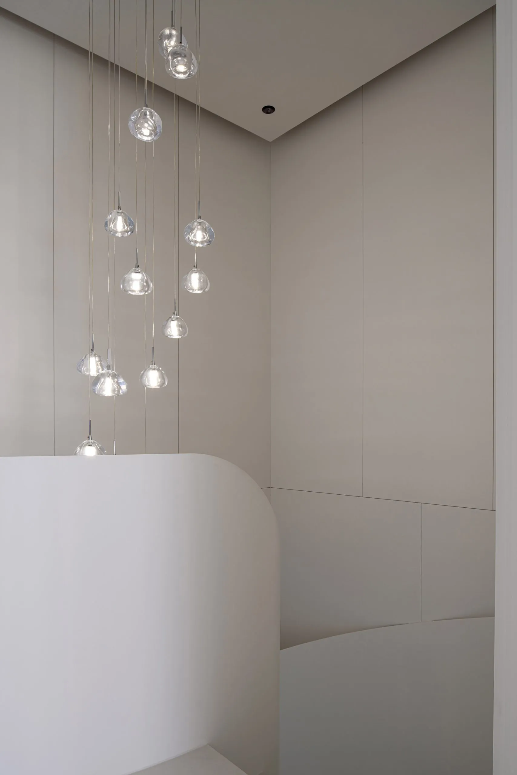 Minimalist bathroom with hanging glass light fixtures and curved white structure