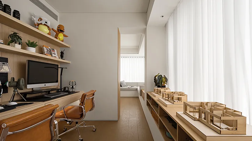 Minimalist office space featuring wooden furniture, white walls, and white curtains with a view to another room with a window