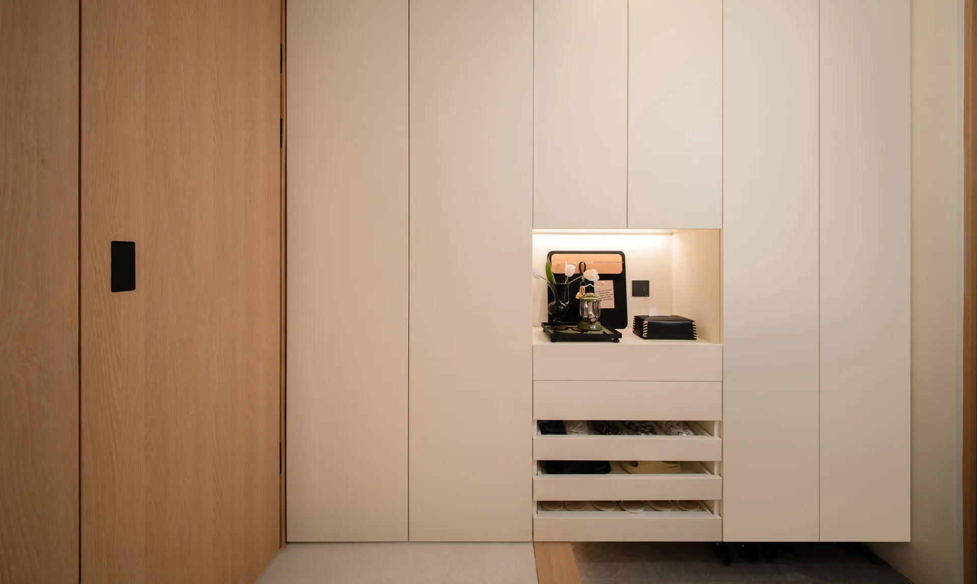 A modern entryway featuring a concrete and white storage system with built-in lighting and drawers.