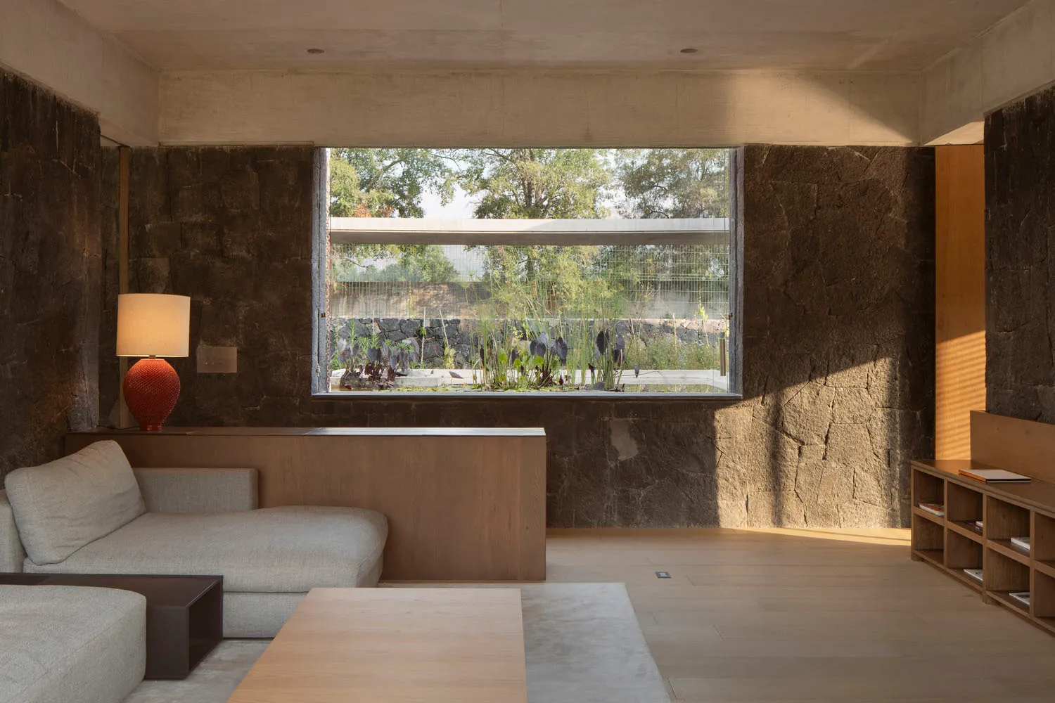 Modern residential living room featuring a large wooden window with a view of outdoor vegetation.