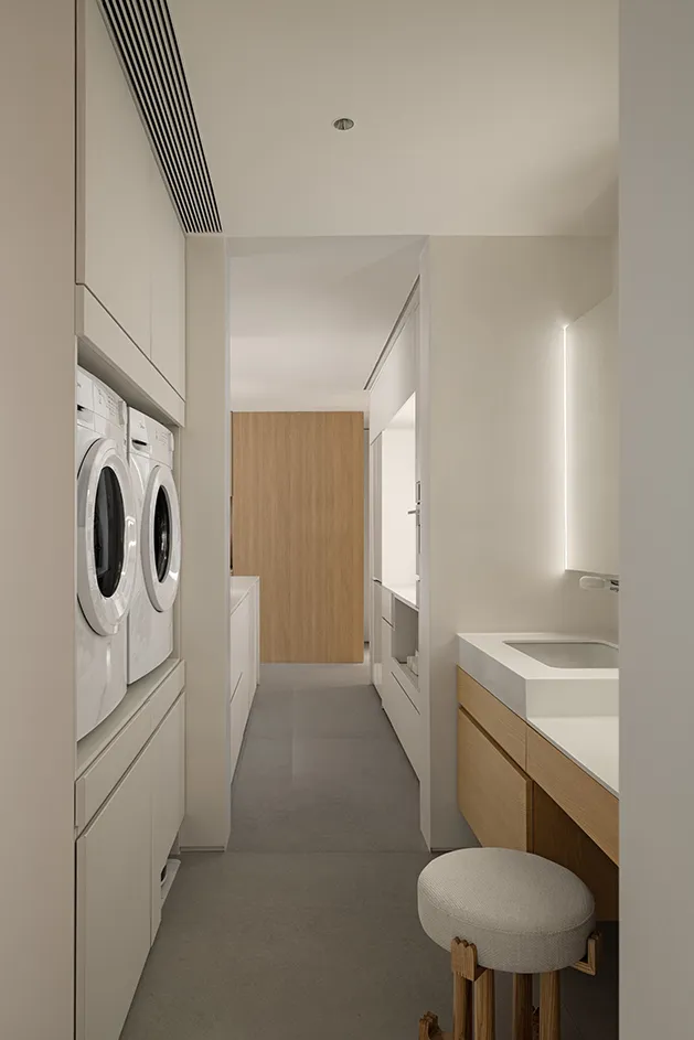 Modern minimalist laundry room featuring white cabinets, oak furniture, and cement floors