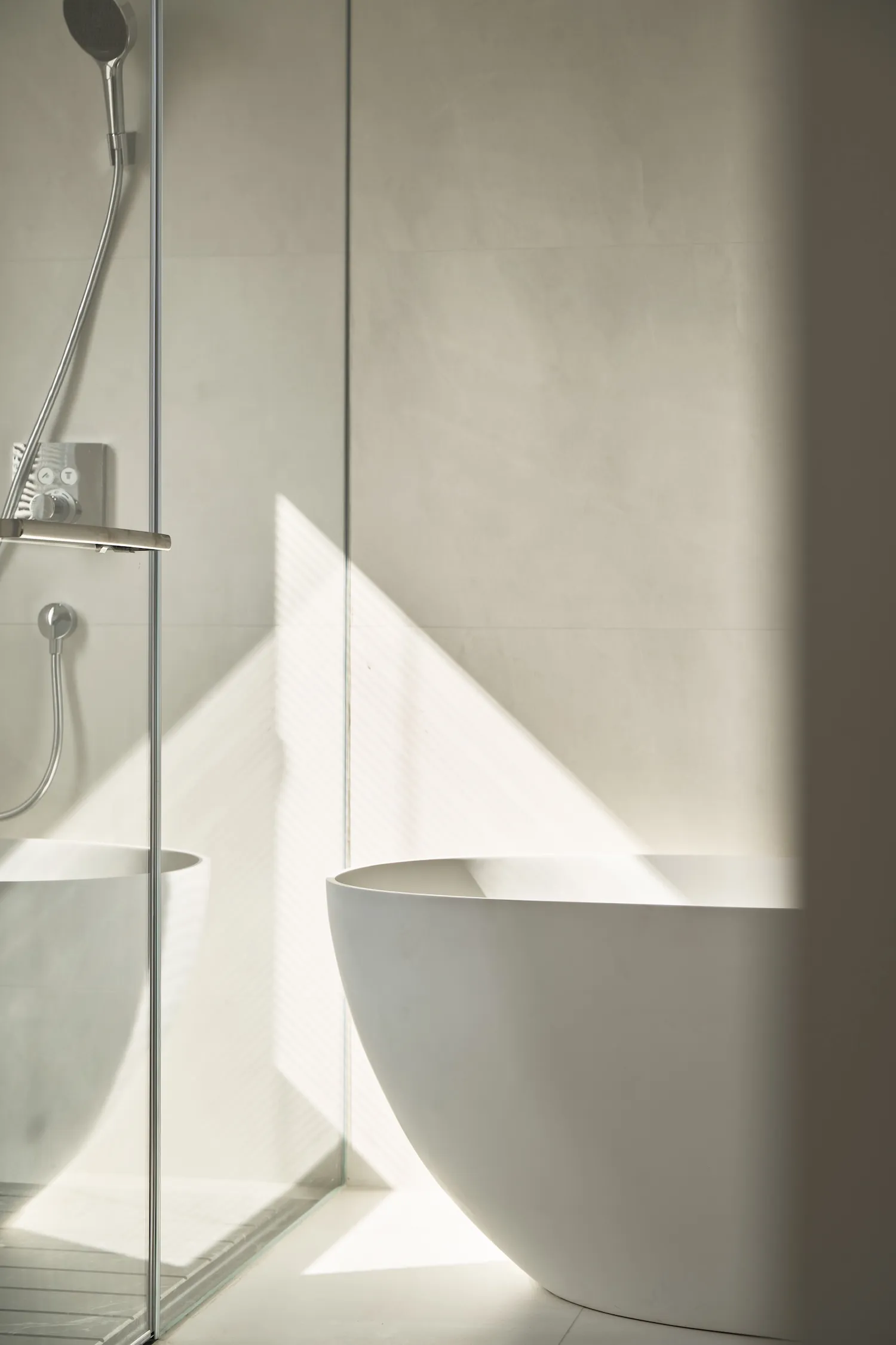 Minimalist white concrete bathroom interior with sunlight casting geometric shadows on the wall.