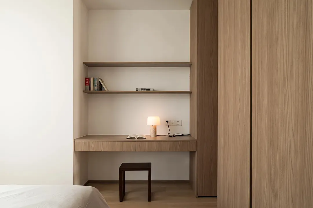 A minimalist bedroom featuring a wooden desk and shelves.
