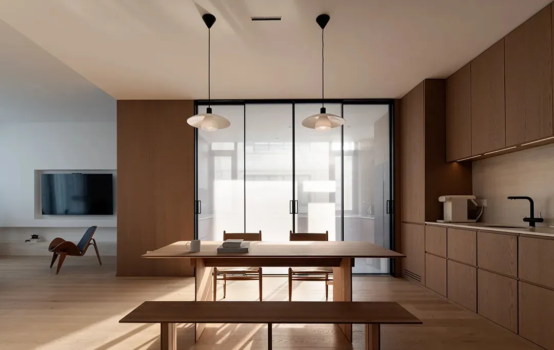 Modern minimalist kitchen with wooden furniture and sliding glass doors.