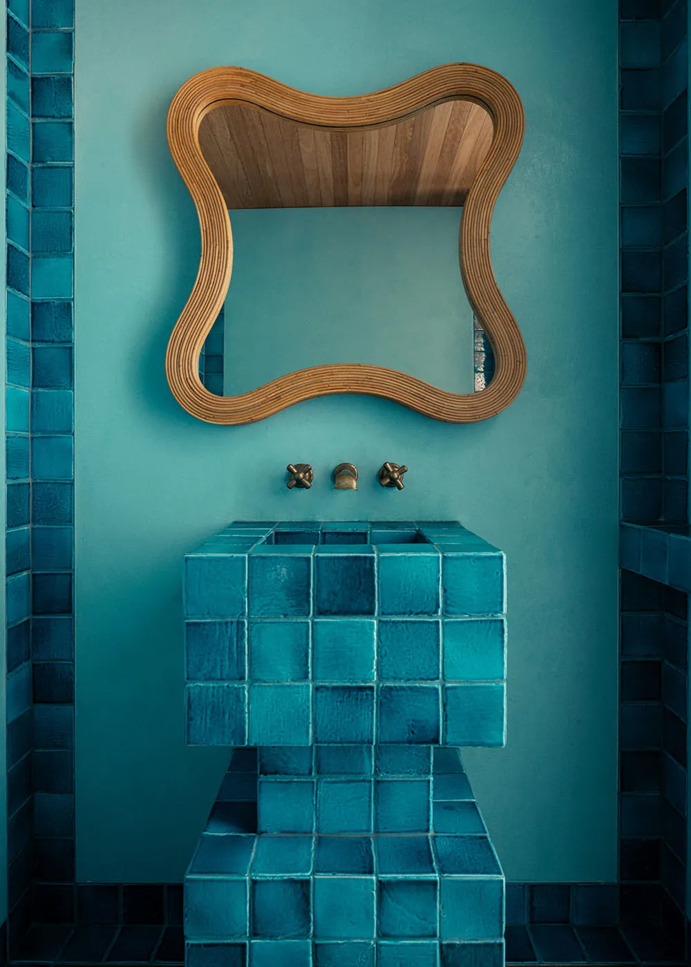 A modern bathroom with blue ceramic tiles and a concrete floor.