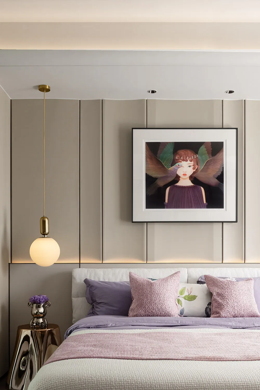 Modern bedroom featuring a bed with blush velvet bedding, white and pink pillows, and a modern chandelier and artwork on the