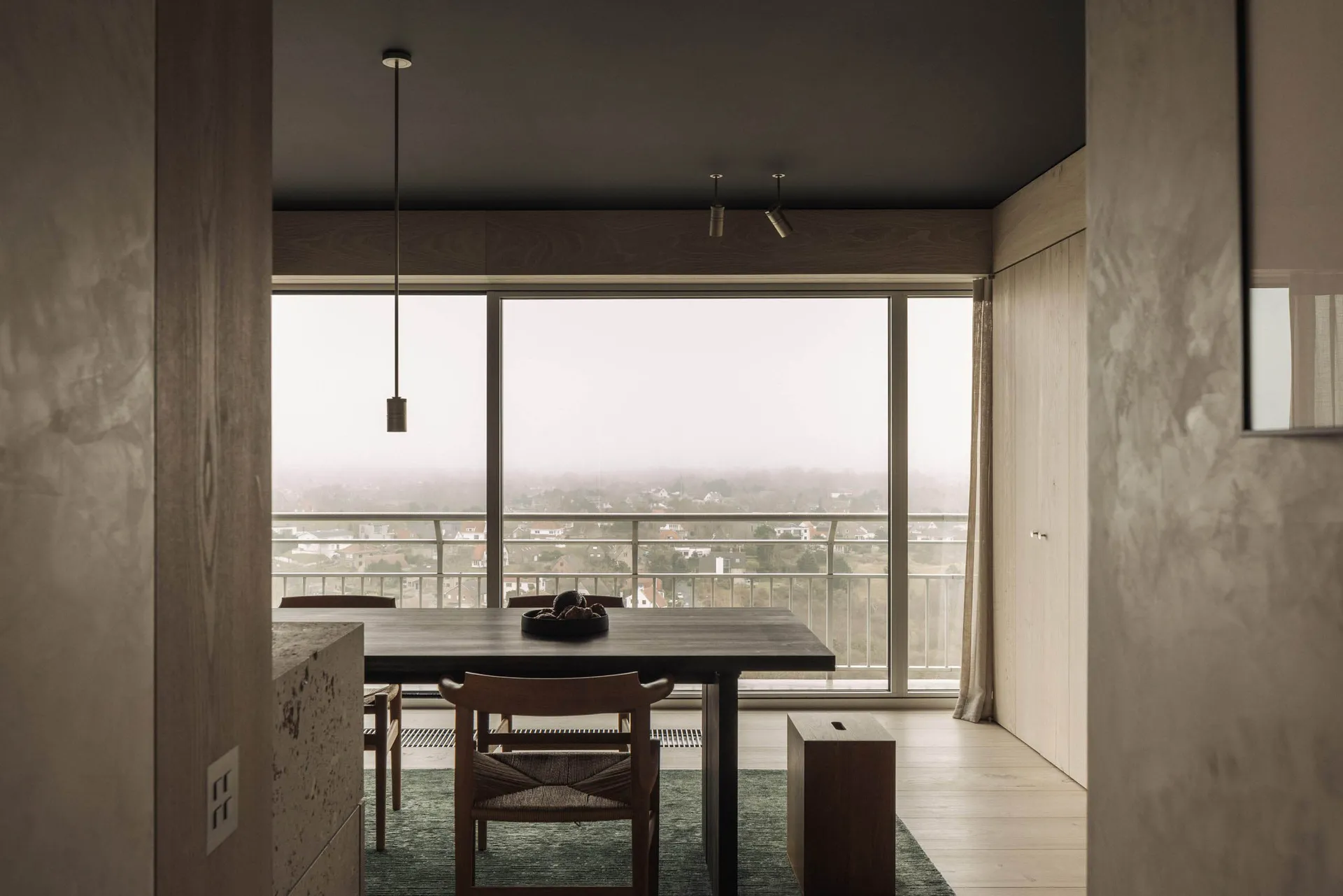 Modern minimalist dining room featuring walnut furniture and large floor-to-ceiling windows.