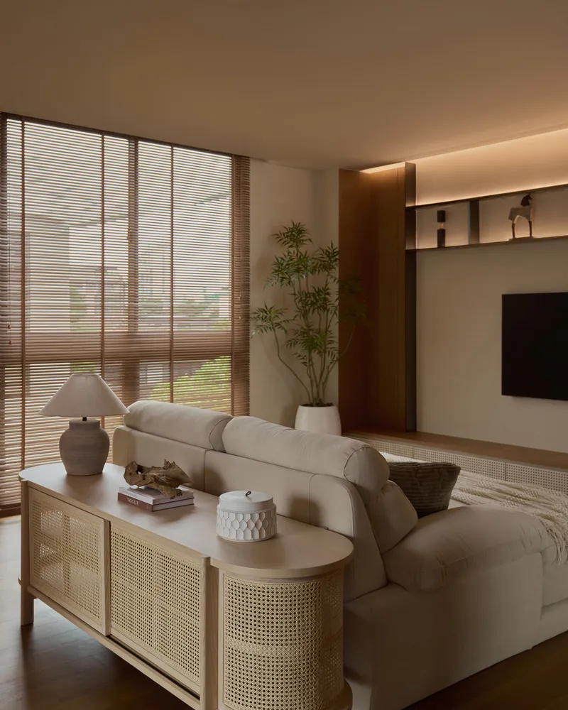 Living room featuring beige furniture, white lamp, potted plant, and a TV stand.