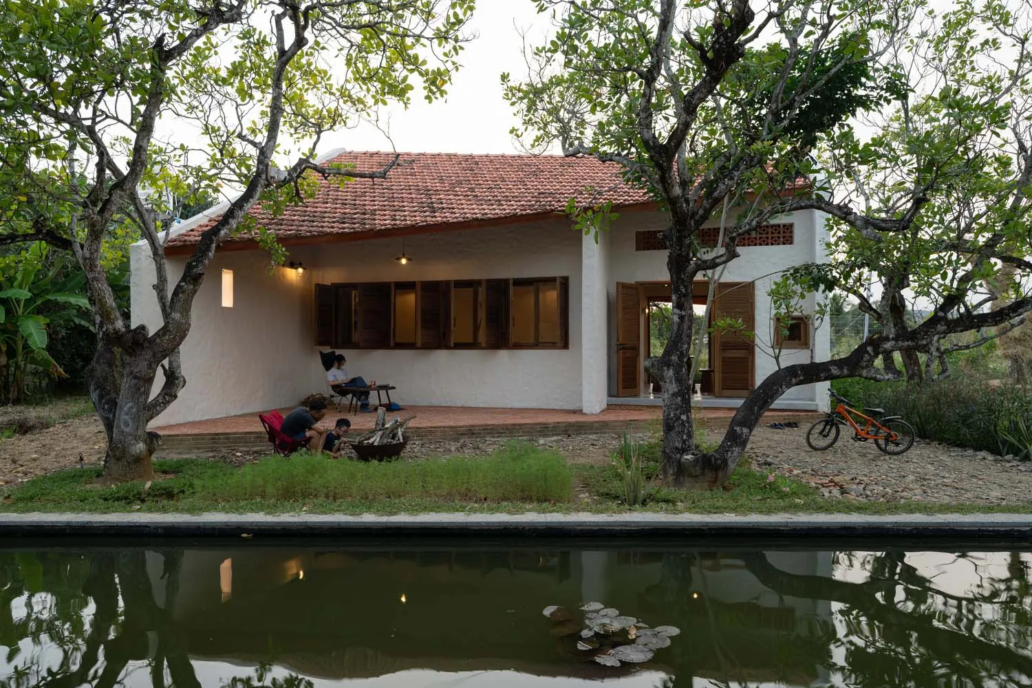A modern residential cottage with a pool surrounded by greenery and a bicycle parked nearby.