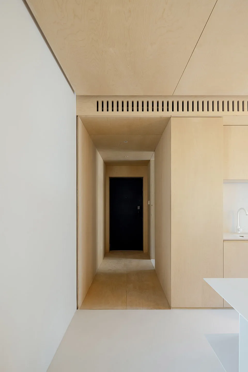 A minimalist apartment with wood paneling and white walls.