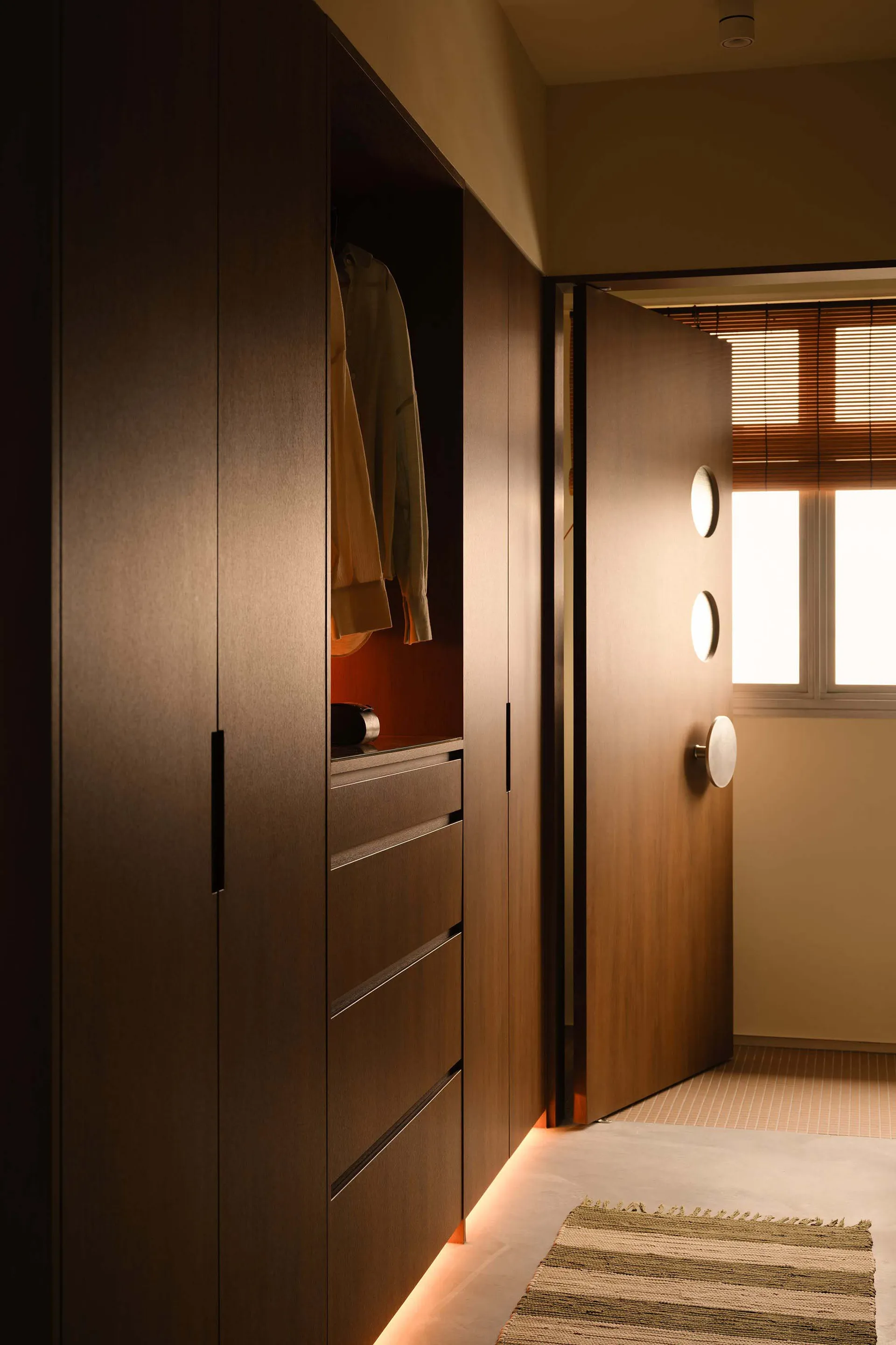 A minimalist closet space featuring wooden cabinets and drawers with a light interior illumination.