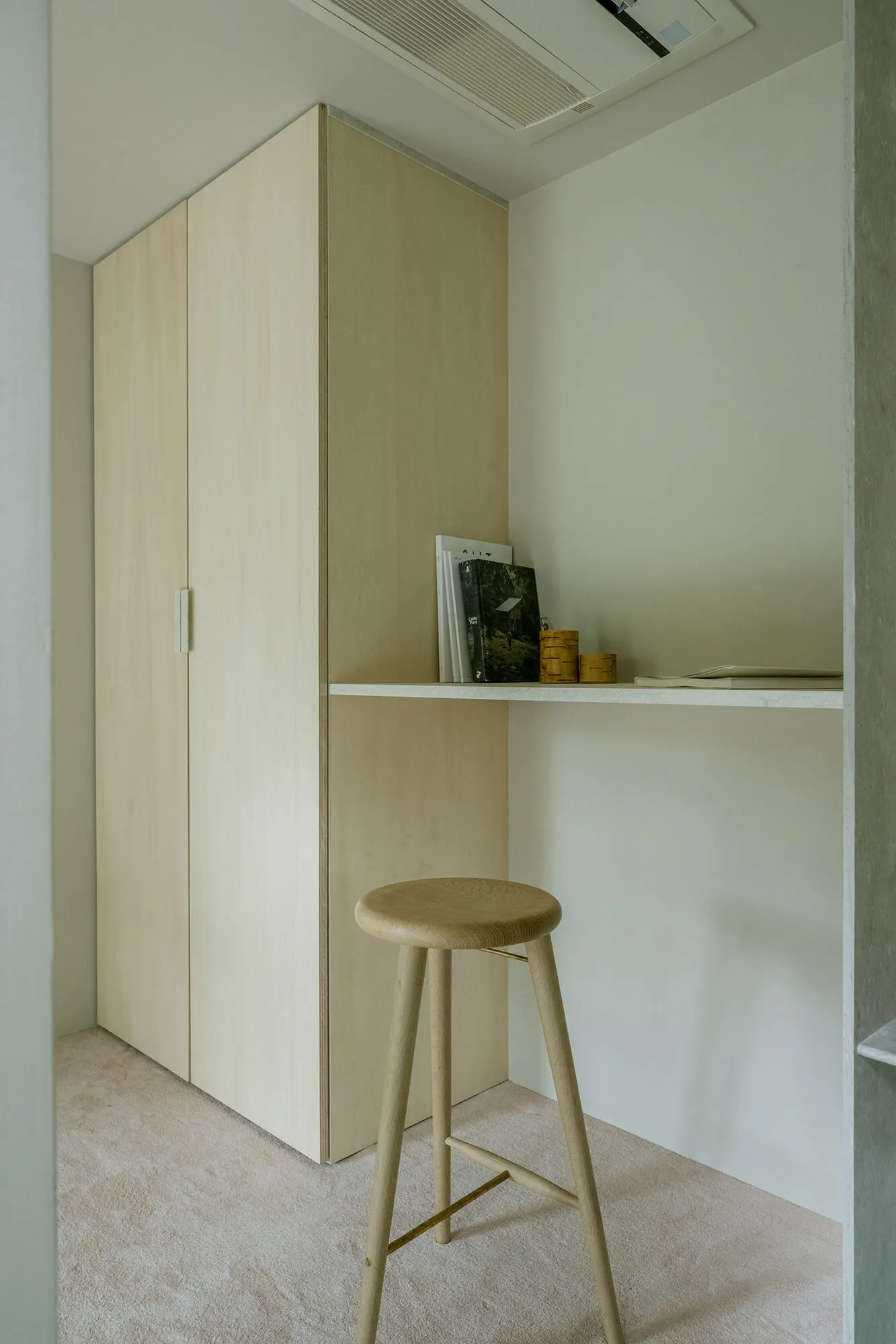 A minimalist home office setup with a wooden desk and stool.