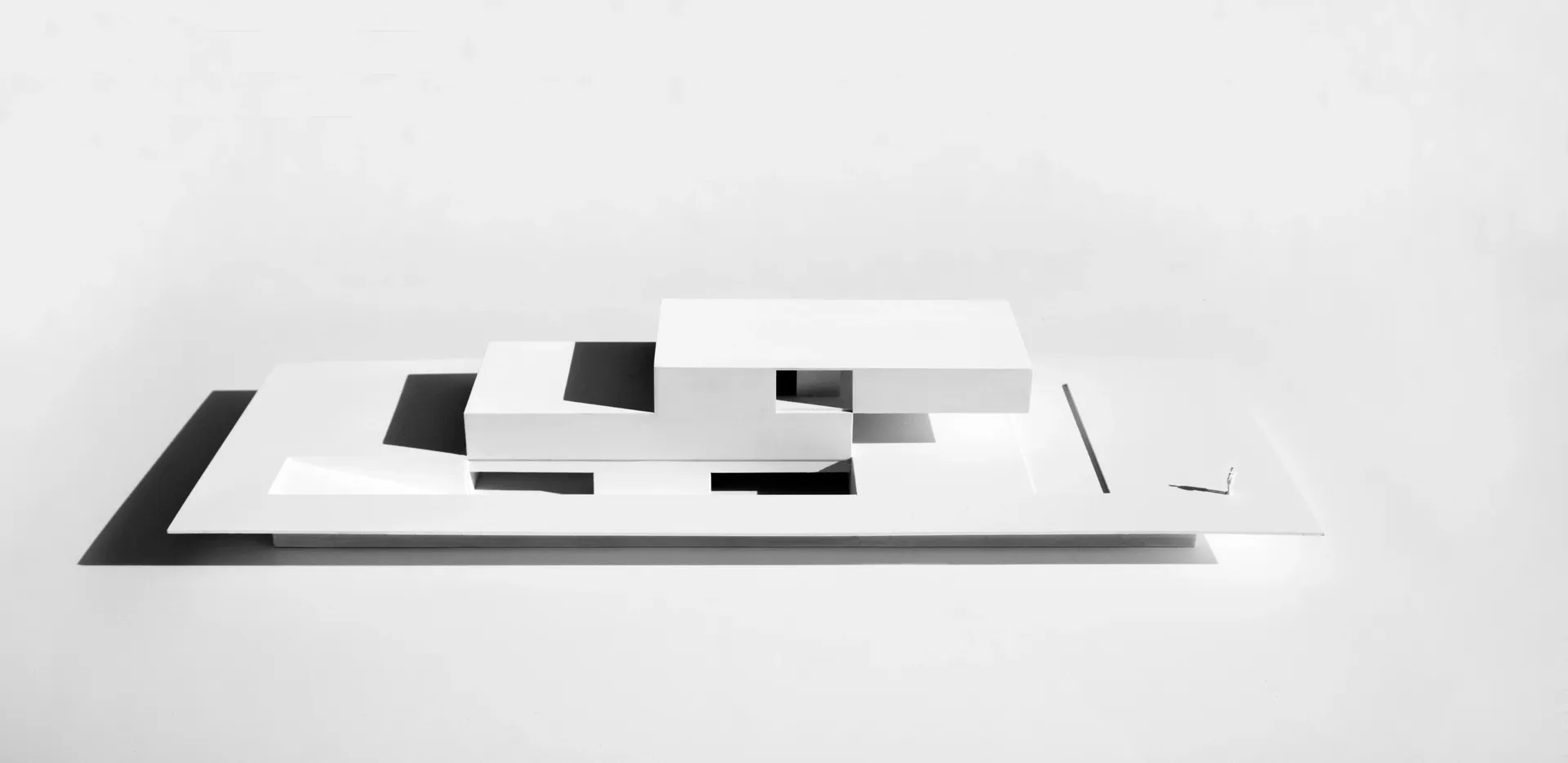 A minimalist architectural model made of white material, featuring clean lines and geometric shapes.