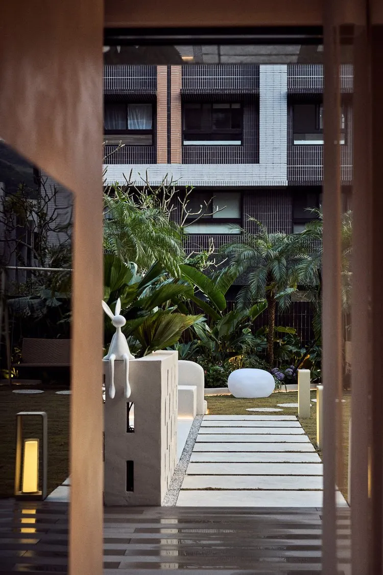 Concrete pathway leading through a modern residential yard surrounded by greenery.