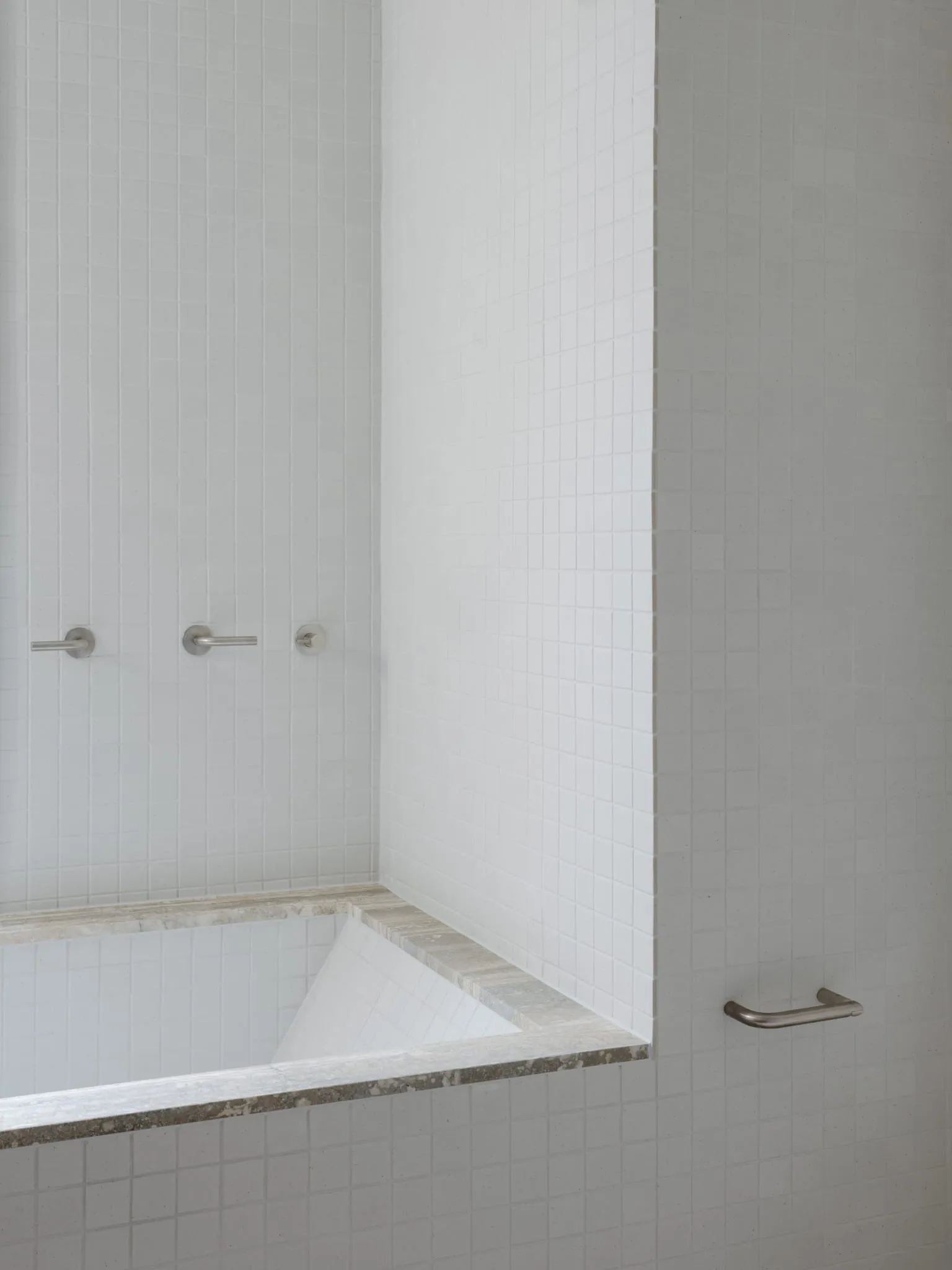 A minimalist bathroom with white tiles and gray concrete accents.