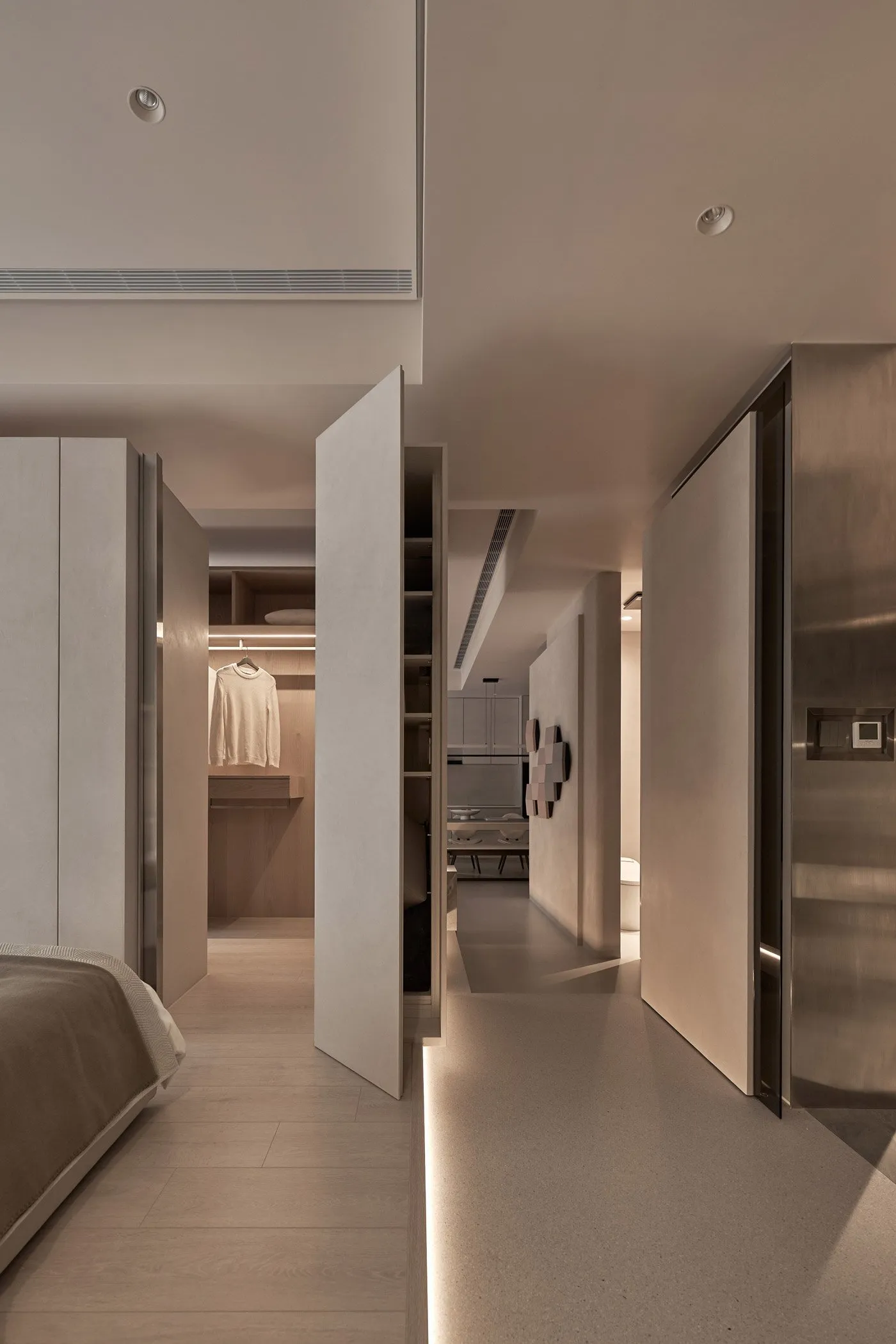 A modern bedroom with a closet featuring neutral-toned materials and minimalist design.