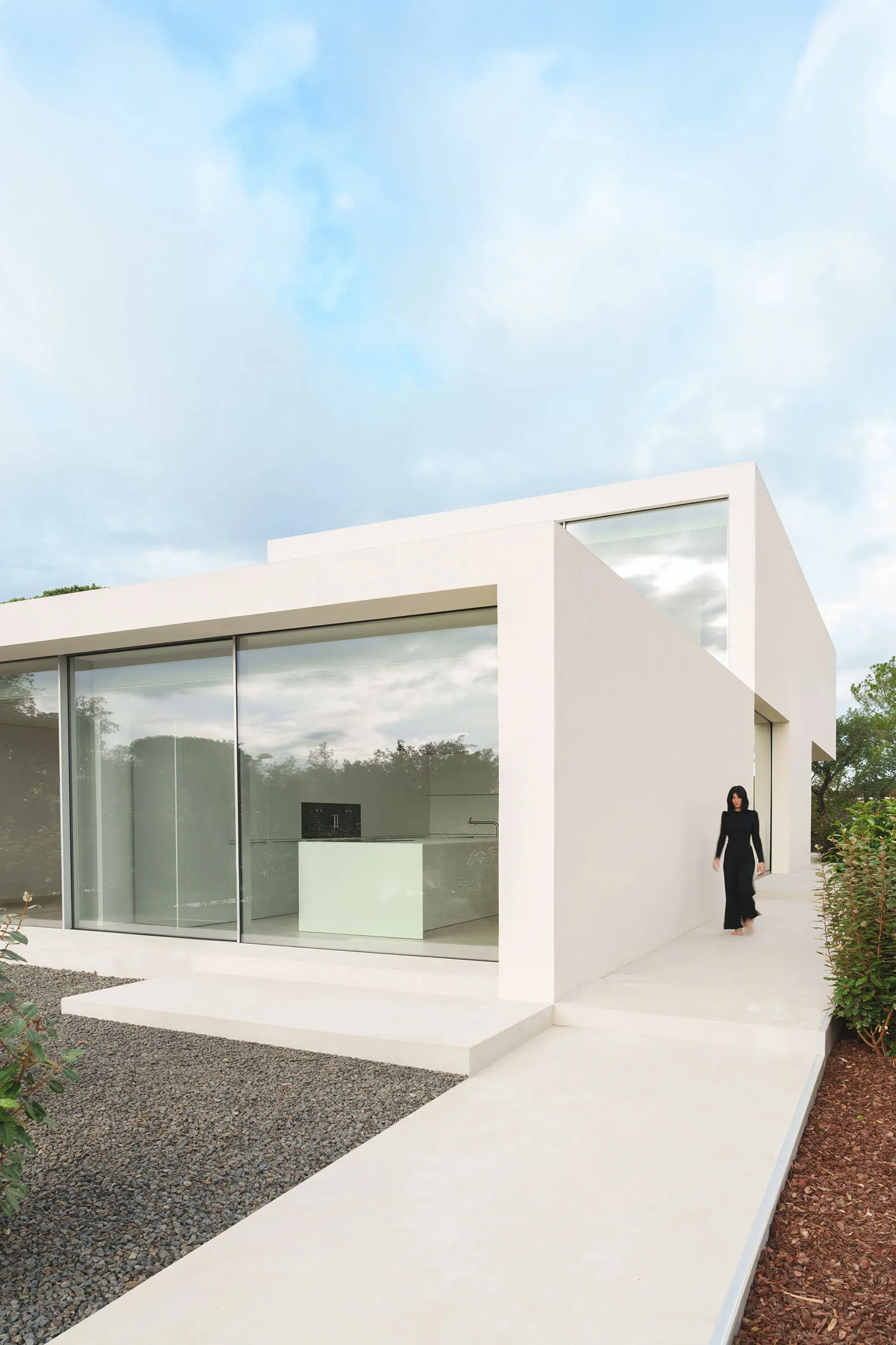 A modern house with a white minimalist design and concrete features.