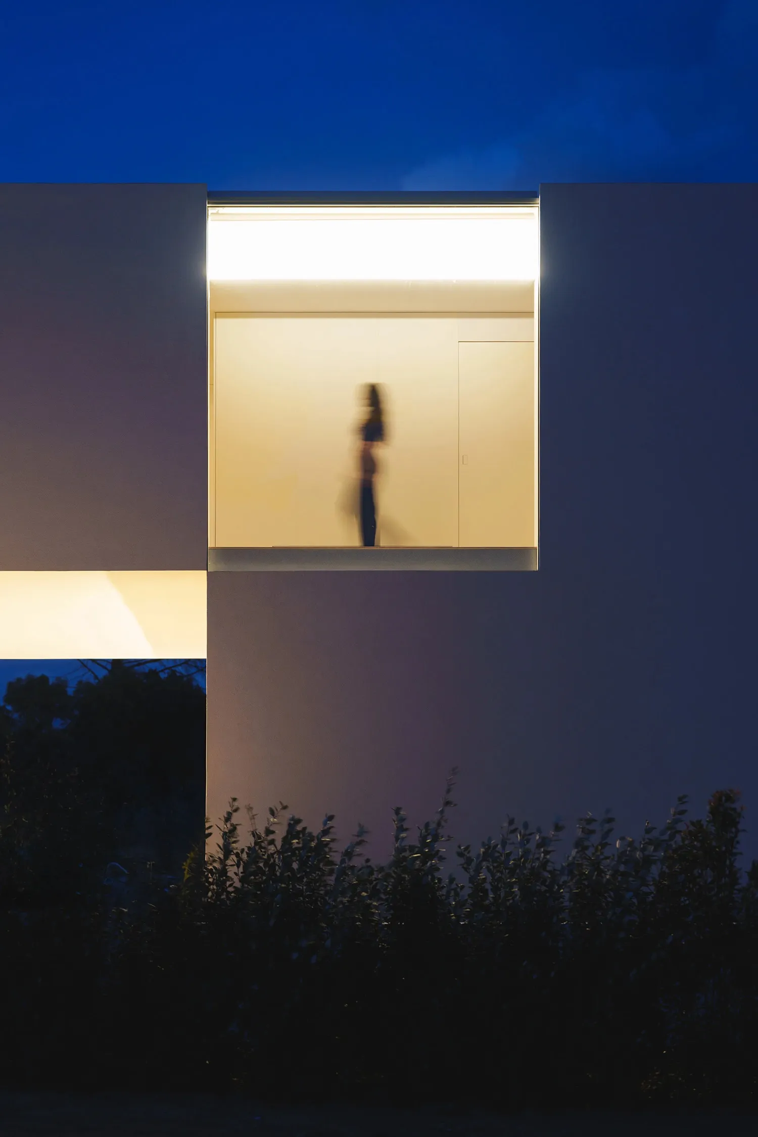 A modern interior home with a glass wall illuminated at night