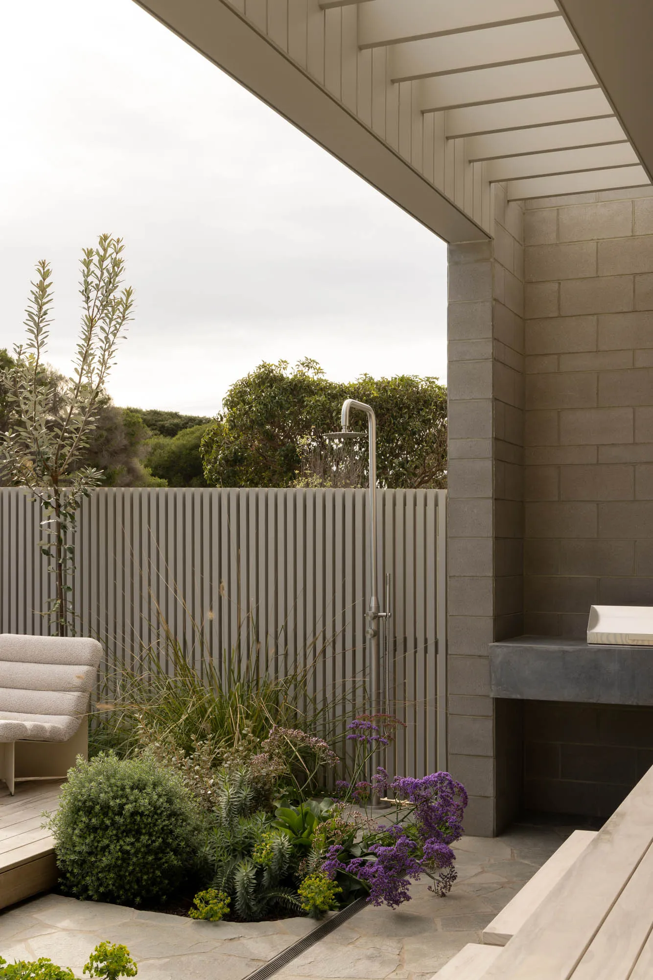 Modern outdoor shower space featuring concrete structures and lush greenery.