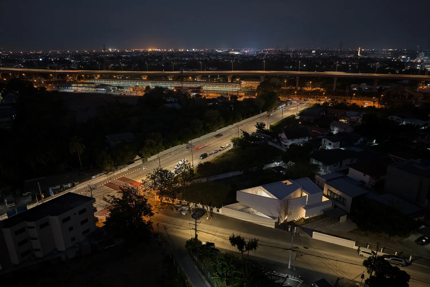 A nighttime aerial view of a city street with illuminated vehicles and buildings.