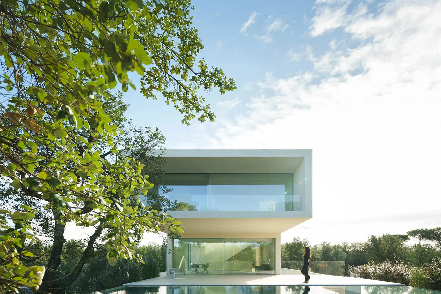 A minimalist house featuring large glass windows and a contemporary white facade.