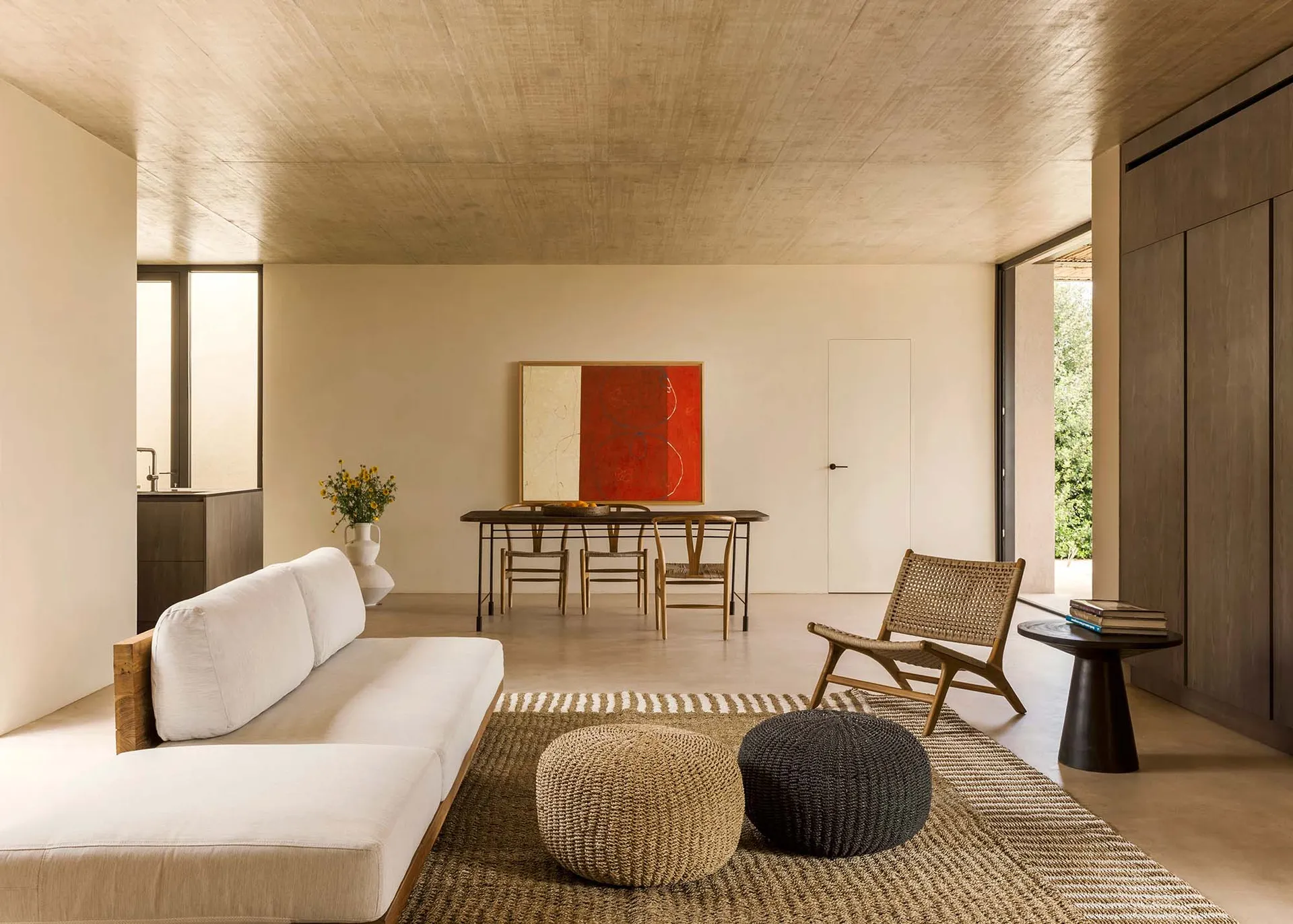 A modern minimalist living room with a white sofa, wooden coffee table, and red painting on the wall.