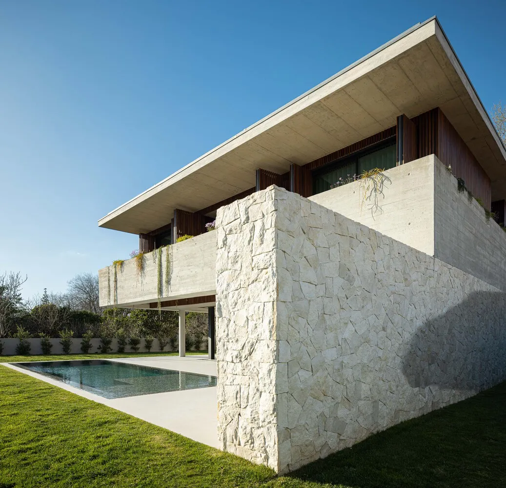 Modern residential house with a concrete exterior and a swimming pool in a green garden.