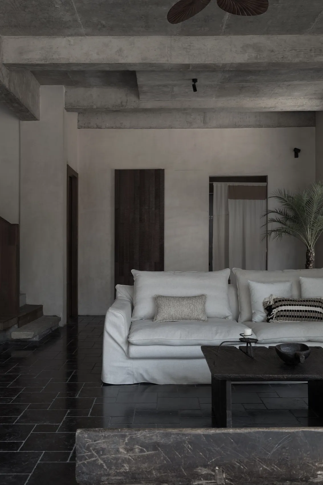 Contemporary living room with minimalist design, concrete flooring, and sleek white furniture.