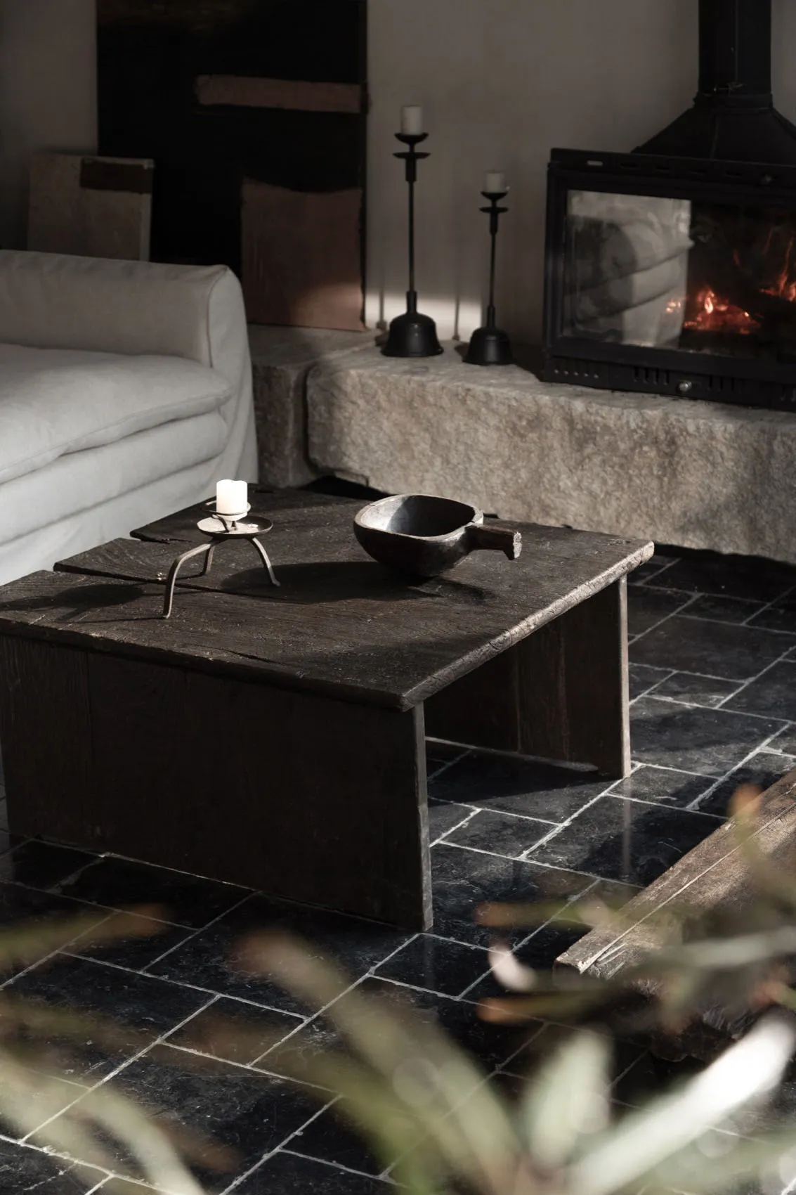 A rustic living room featuring a wooden table with a stone fireplace in the background.