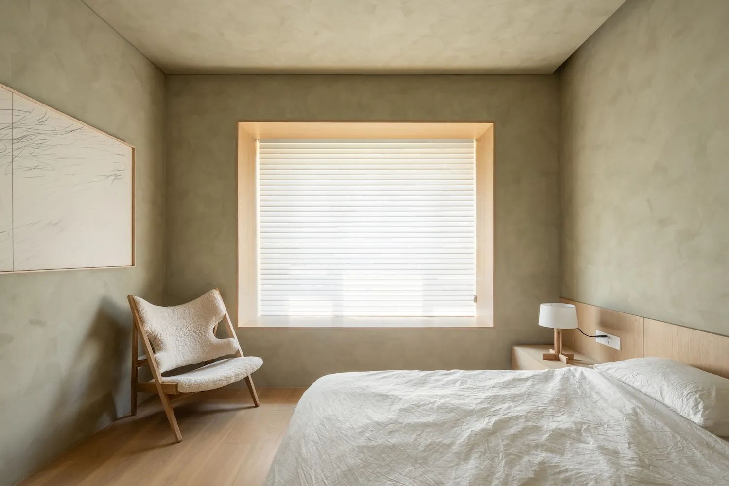 Minimalist bedroom with wooden furniture, concrete walls, and soft textiles