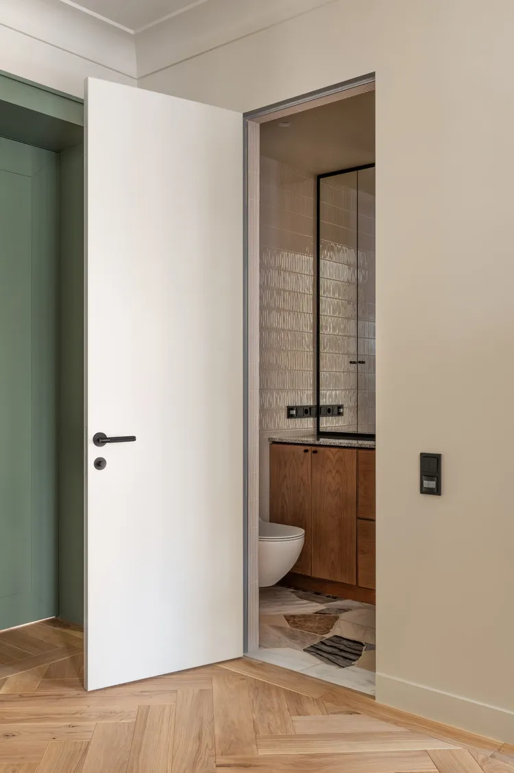 A modern bathroom featuring wooden flooring, glass doors, and ceramic tiles on the walls.