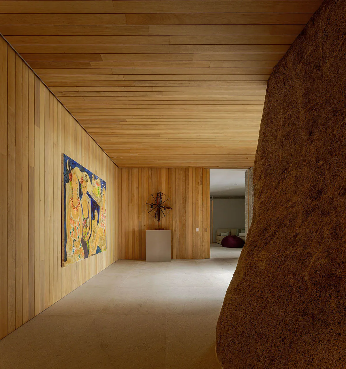 Modern living room featuring wooden walls and ceiling, a colorful painting, and a rock-like structure