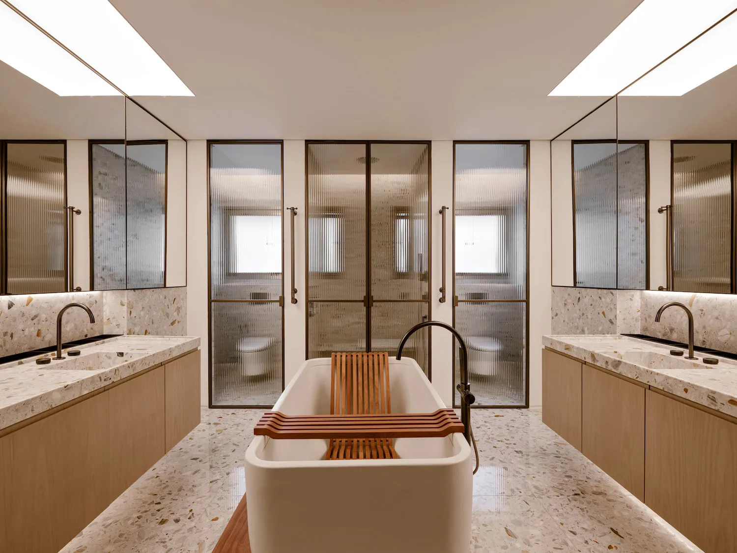 Modern minimalist bathroom featuring a free-standing white bathtub with a wooden tray, surrounded by terrazzo marble countert