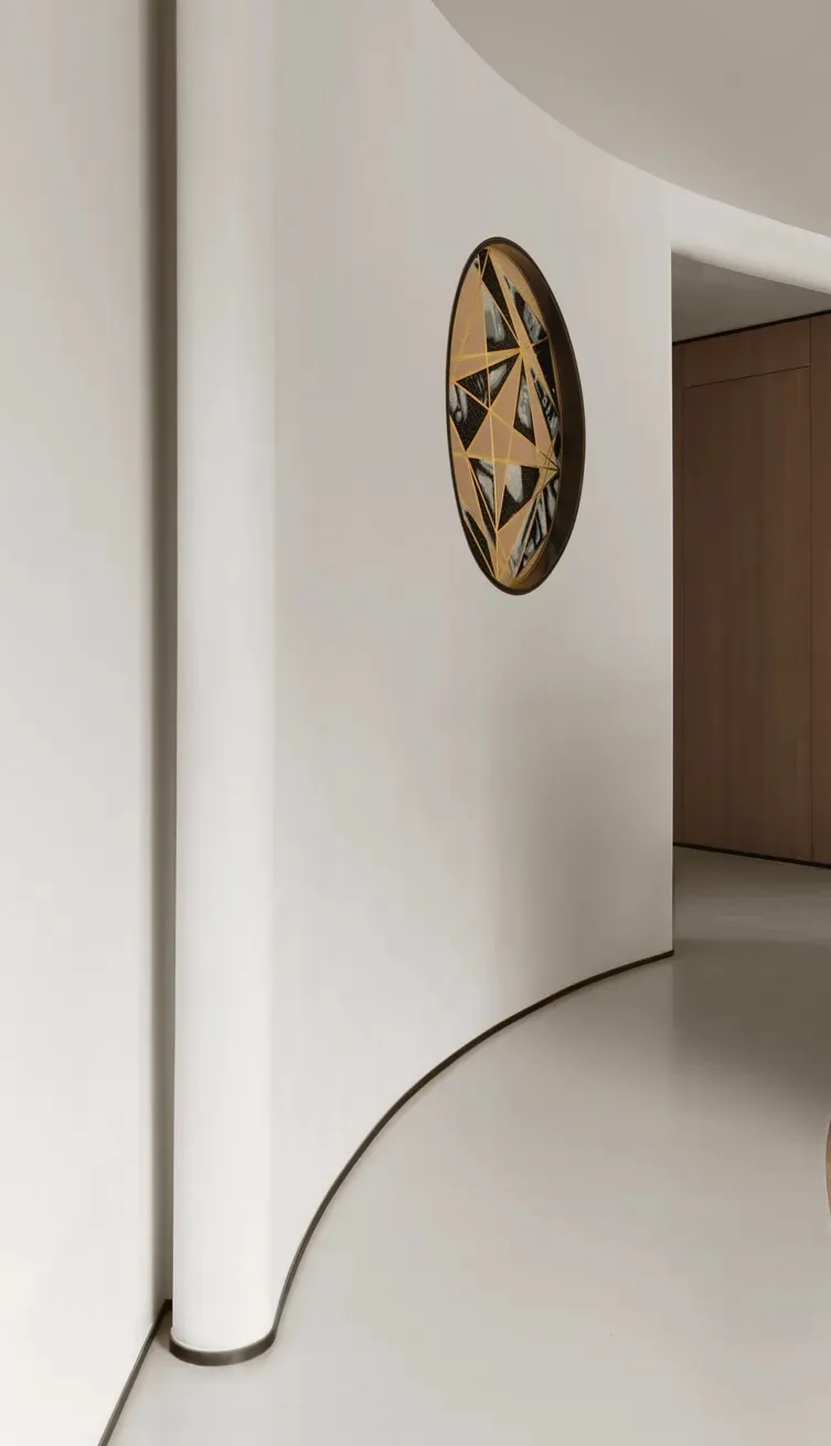 A modern decorative metal circle with geometric patterns on a white wall in a minimalist interior design setting.