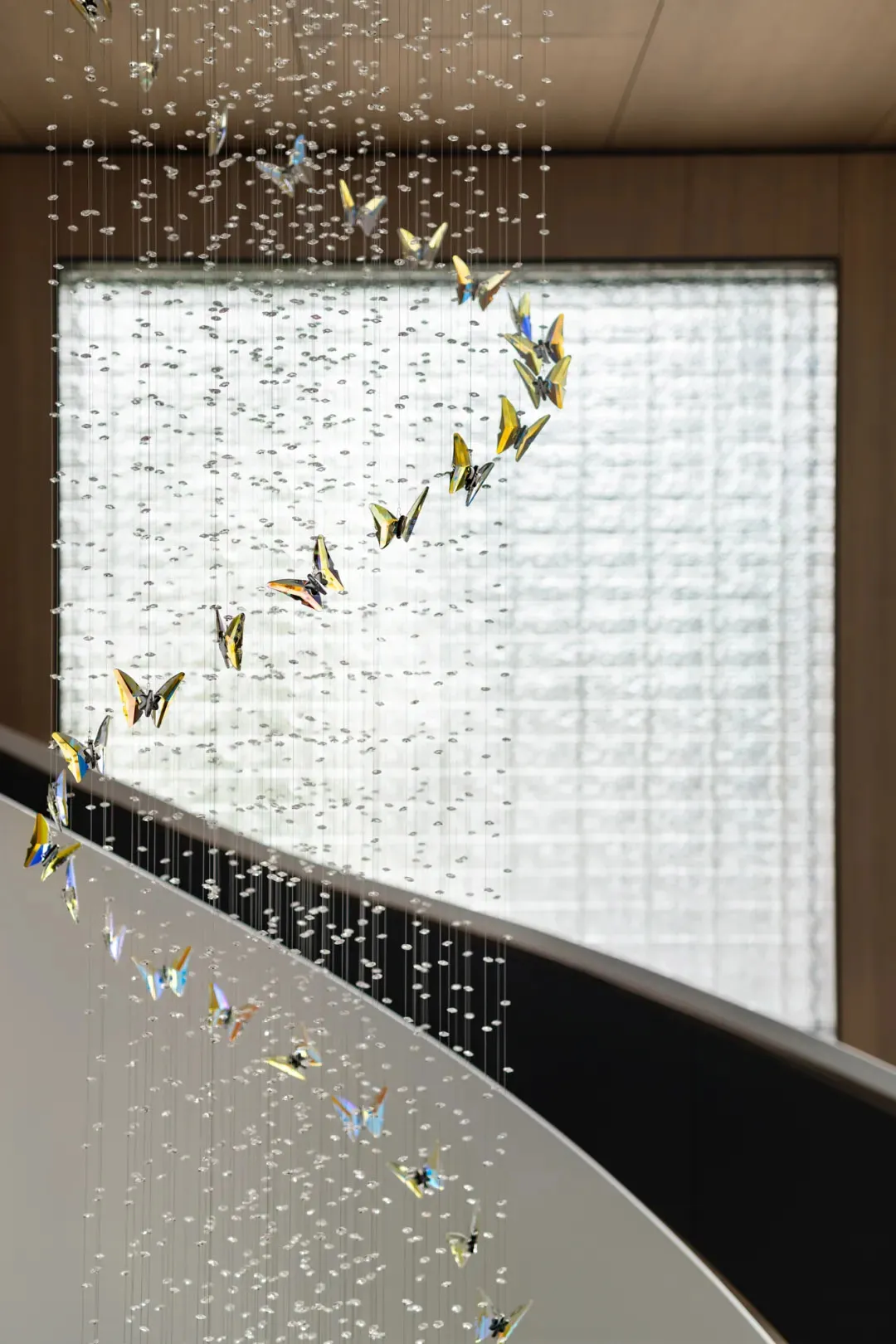 A contemporary glass chandelier sculpture hanging from the ceiling in an elegant interior space.