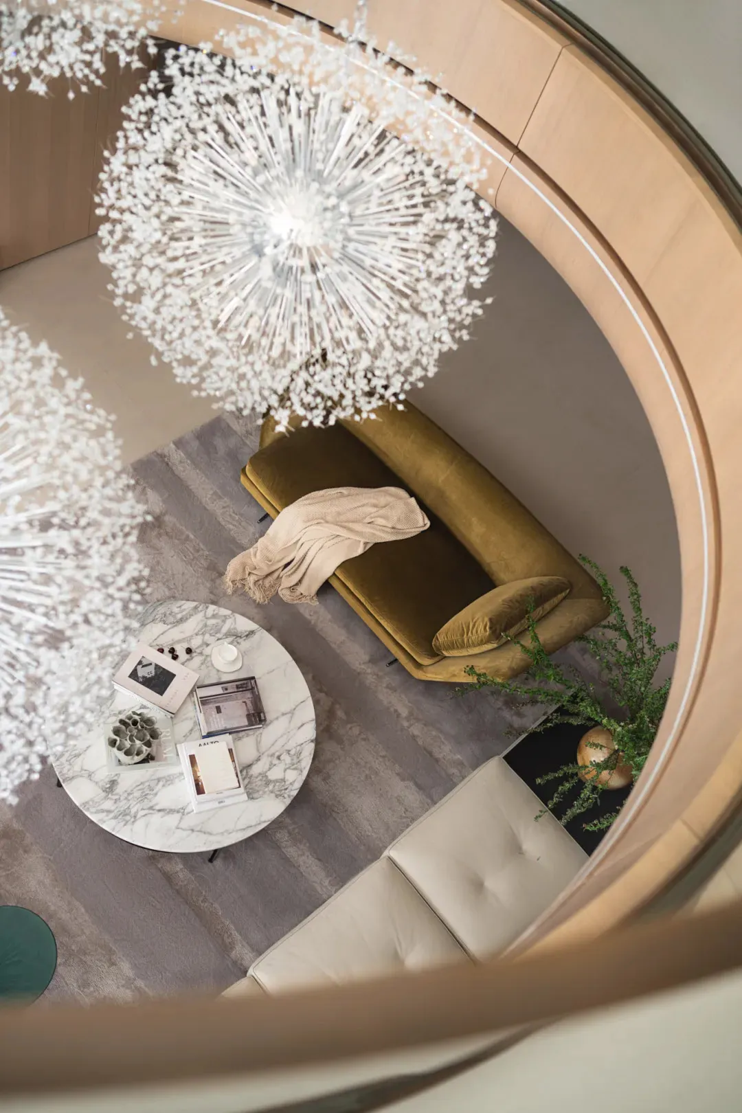 Modern, minimalist living room with beige leather sofa, marble coffee table, and contemporary chandeliers.