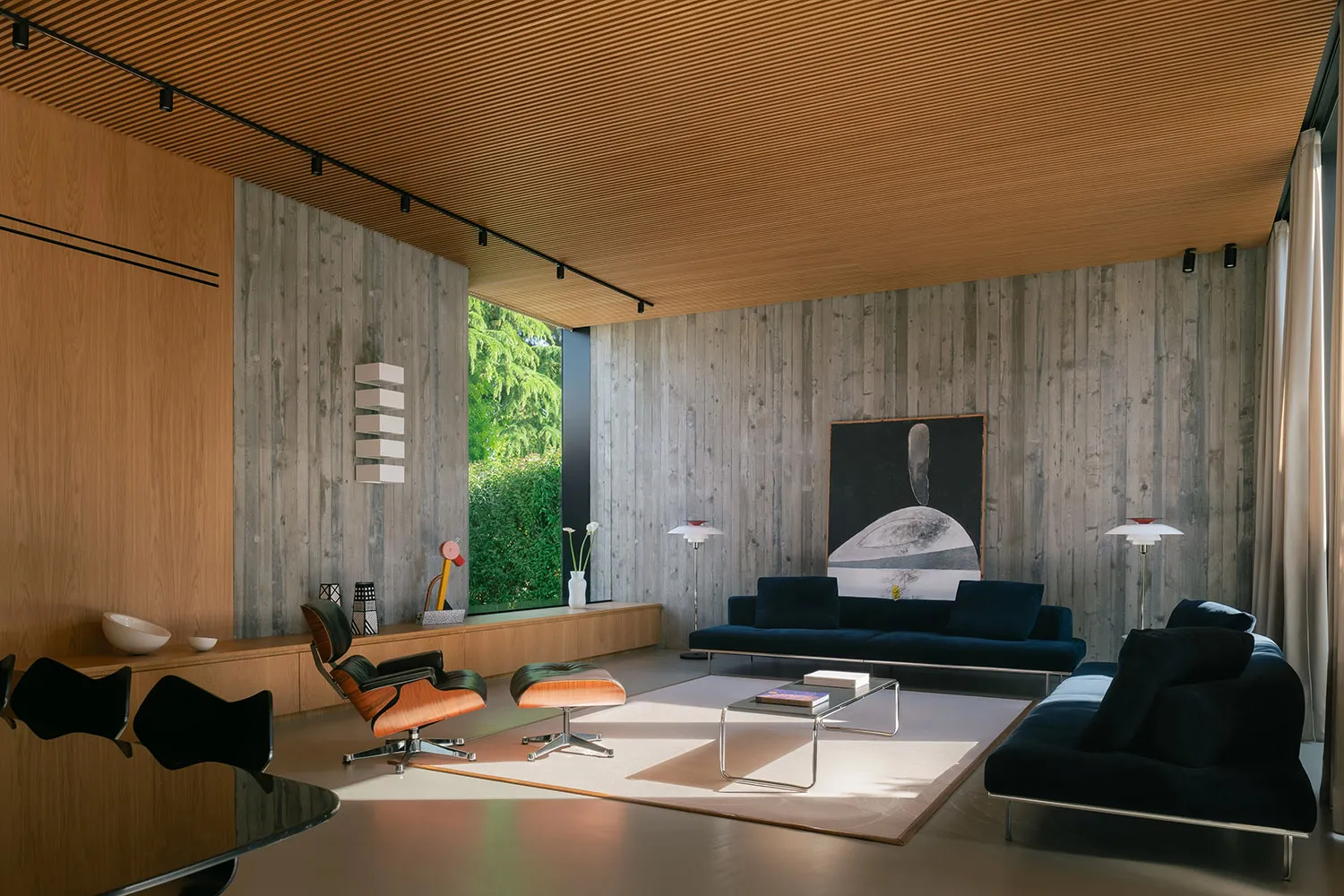 A modern residential space featuring concrete walls and a large window.
