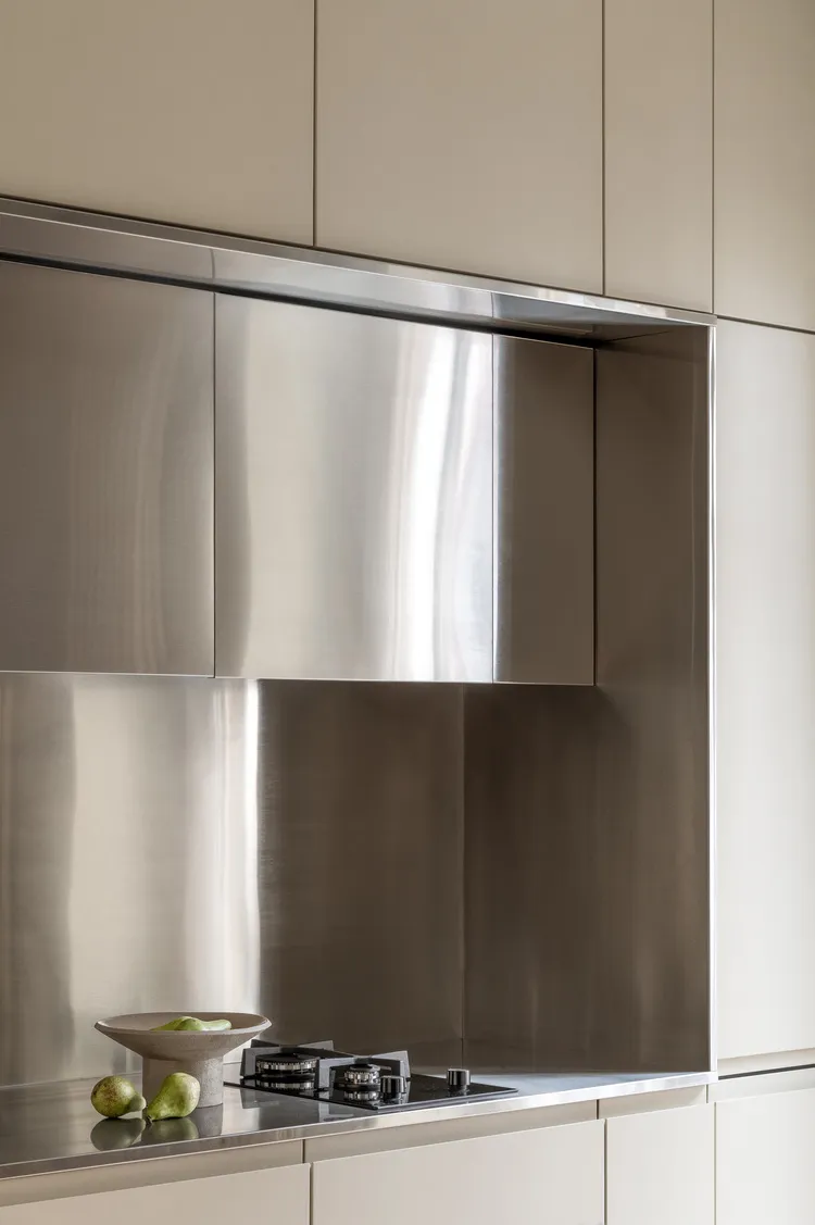 A minimalist kitchen with metal cabinets, a stainless steel backsplash, and a countertop.