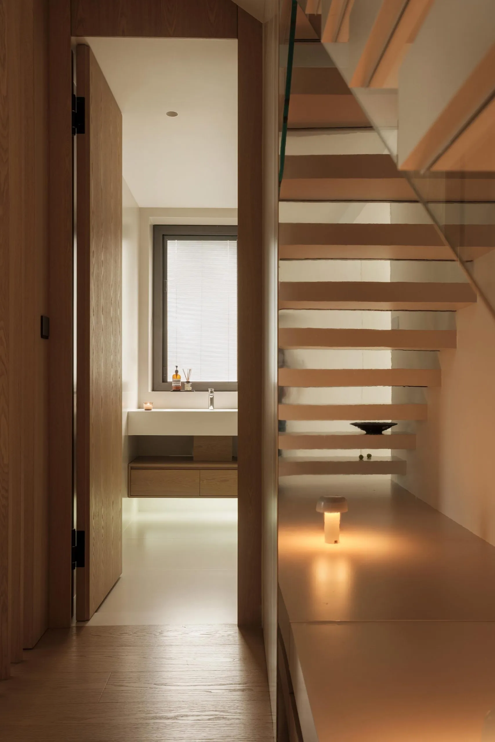A modern bathroom featuring a minimalist design with wooden elements and sleek white surfaces.