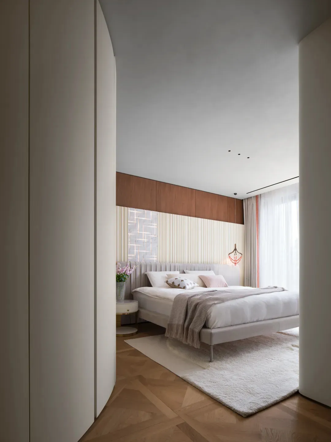 Modern bedroom featuring white furniture, wood floors, and a minimalist design.