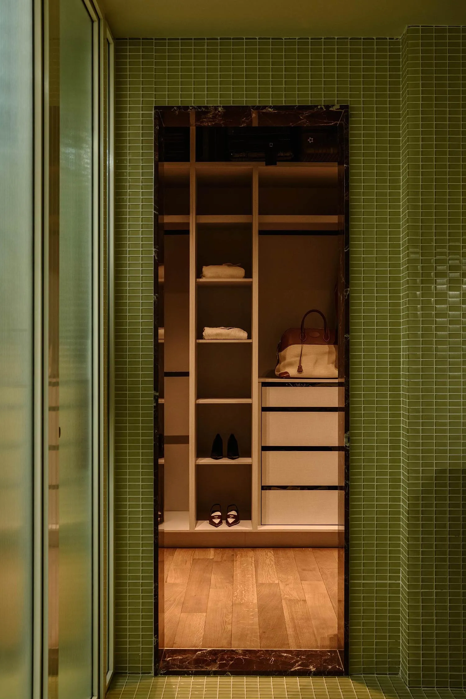 Modern closet storage area with wood tiles and marble accents, featuring organized shelves and drawers.