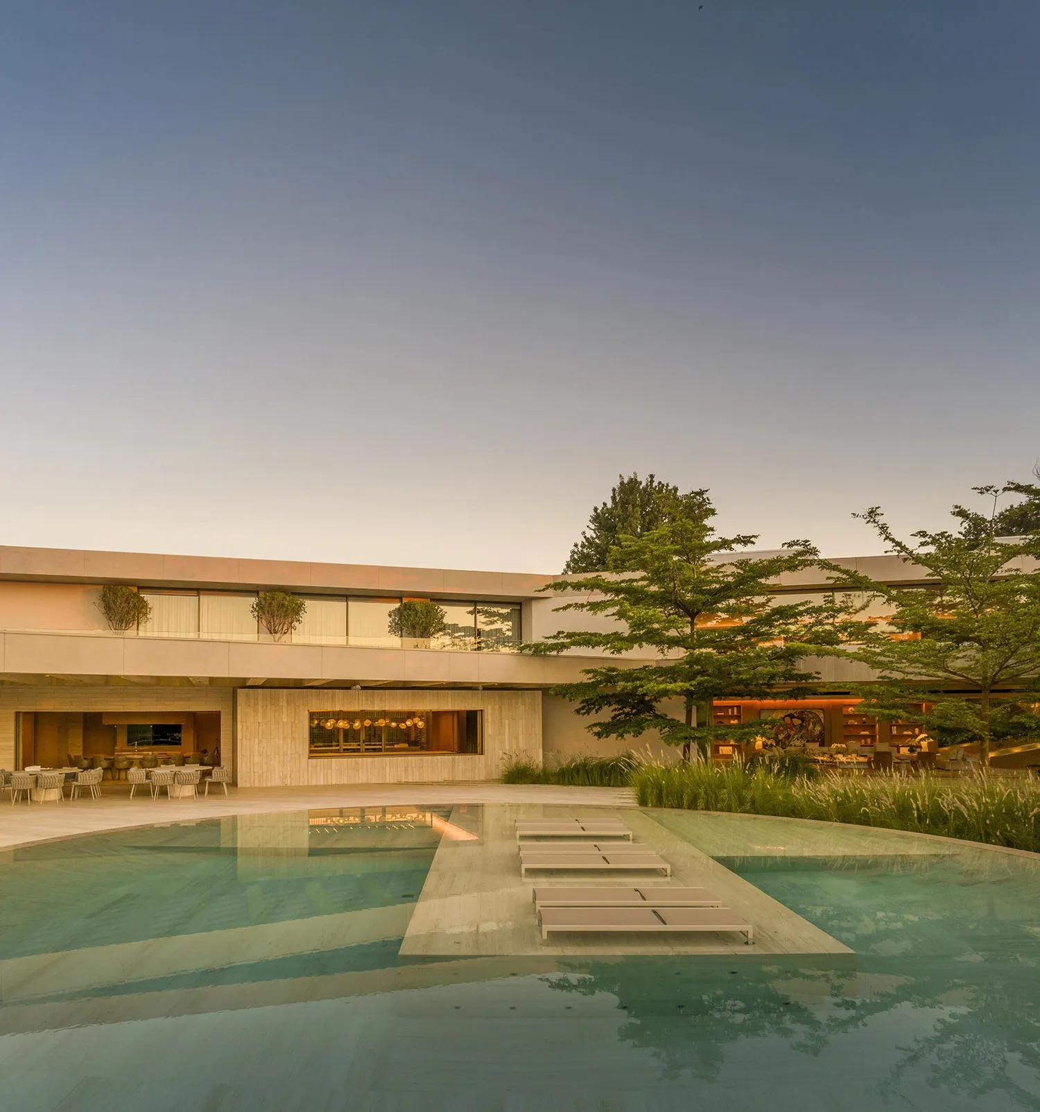 Modern hotel architecture featuring clean lines, large glass windows, and a serene outdoor pool area.