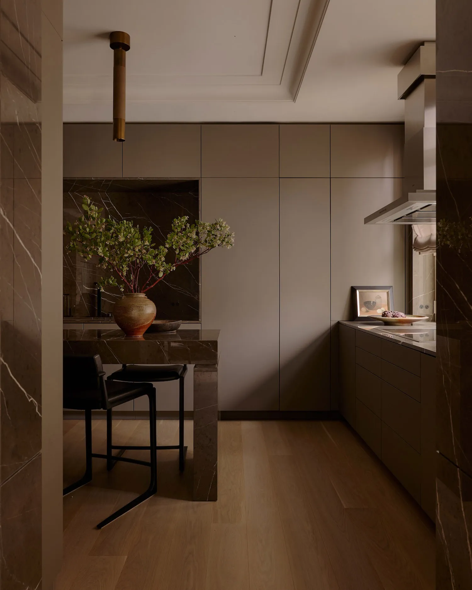 Modern kitchen with marble countertops, wood flooring, and minimalist design.