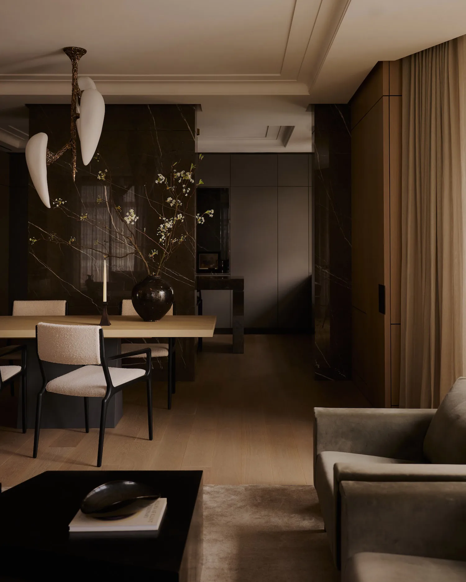 A modern residential dining room with a wooden floor, marble accent wall, and upholstered furniture.