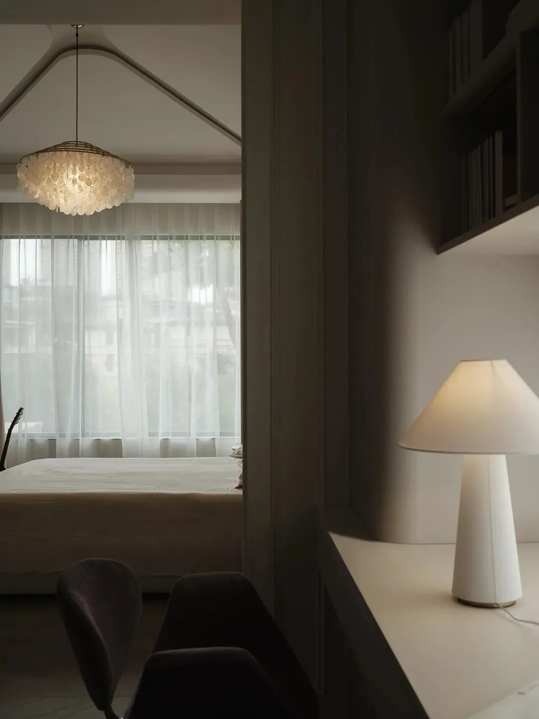 A minimalist bedroom featuring wooden flooring and fabric textiles.