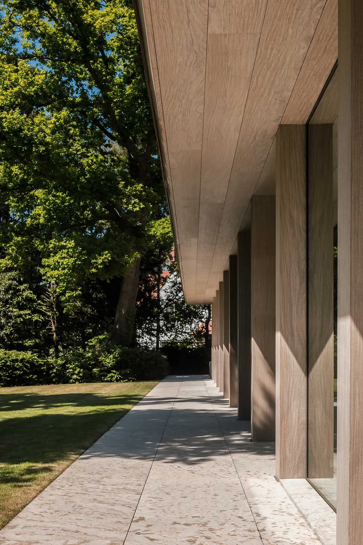 A walkway with wooden columns and a sloped wooden roof in a modern architectural setting