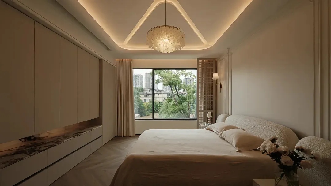 Contemporary bedroom with white bed, marble headboard, and fabric bedding, featuring a large window overlooking greenery